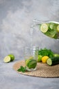 Pouring tasty fresh cucumber water from bottle into glass. A bottle of clean, cool and fresh drink stands on a gray Royalty Free Stock Photo