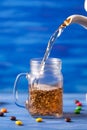 Pouring tea on blue background on blue wooden table with sugar and sweets. Drink flows from glass jar. Tea is pouring from a jug Royalty Free Stock Photo