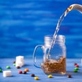 Pouring tea on blue background on blue wooden table with sugar and sweets. Drink flows from glass jar. Tea is pouring from a jug Royalty Free Stock Photo