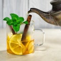 Pouring tea from a teapot into a cup with lemon, cinnamon and mint Royalty Free Stock Photo