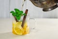 Pouring tea from a teapot into a cup with lemon, cinnamon and mint Royalty Free Stock Photo