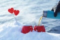 Pouring tea from a thermos in the on a picnic on Valentine`s Day. Red mugs with hot tea, lollipops hearts in the snow