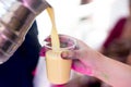 Pouring thandai from a steel flask into a disposable cup