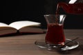 Pouring traditional Turkish tea from pot into glass on wooden table, space for text Royalty Free Stock Photo