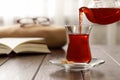 Pouring traditional Turkish tea from pot into glass on wooden table, space for text Royalty Free Stock Photo