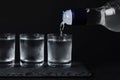Pouring vodka from bottle in glass on black table Royalty Free Stock Photo