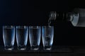 Pouring vodka from bottle in glass on black table Royalty Free Stock Photo