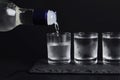 Pouring vodka from bottle in glass on black table Royalty Free Stock Photo