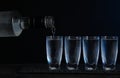 Pouring vodka from bottle in glass on black table Royalty Free Stock Photo