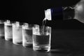Pouring vodka from bottle in glass on grey table, closeup Royalty Free Stock Photo