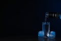 Pouring vodka from bottle in glass and ice cubes on black background. Space for text Royalty Free Stock Photo