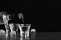 Pouring vodka from bottle in glass and ice cubes on grey table. Space for text Royalty Free Stock Photo