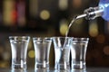 Pouring vodka from bottle into shot glass on counter Royalty Free Stock Photo