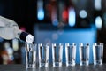Pouring vodka from bottle into shot glasses on counter Royalty Free Stock Photo
