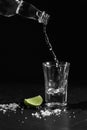 Pouring vodka into the shot glass on a black background with a blank space for a text Royalty Free Stock Photo