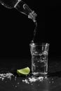 Pouring vodka into the shot glass on a black background with a blank space for a text Royalty Free Stock Photo