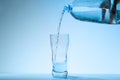 Pouring water from bottle into glass against background. Refreshing drink Royalty Free Stock Photo