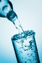 Pouring water from a bottle into glass on a blue background Royalty Free Stock Photo
