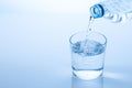 Pouring water from the bottle in to the glass isolated on blue background with copy space Royalty Free Stock Photo