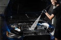 Pouring water on car engine. Washing car engine with spray, brush and detergent in detailing auto service. Detailing Royalty Free Stock Photo