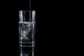 Pouring water into glass on black background Royalty Free Stock Photo