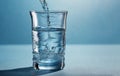 Pouring water into a glass on blue background, close-up Royalty Free Stock Photo