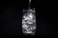 Pouring water in glass with crushed ice on black background Royalty Free Stock Photo