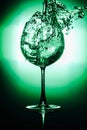 Pouring water into glass and splash out of a glass isolated on bright green and black background Royalty Free Stock Photo