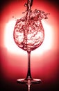 Pouring water into glass and splash out of a glass isolated on bright red and black background Royalty Free Stock Photo