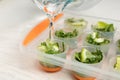 Pouring water into ice cube tray with lime slices and mint on table Royalty Free Stock Photo