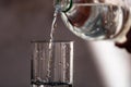 Pouring water from plastic bottle into a glass on blurred background. Selective focus and copy space Royalty Free Stock Photo