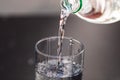 Pouring water from plastic bottle into a glass on blurred background. Selective focus and copy space Royalty Free Stock Photo