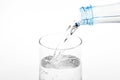 Pouring water from plastic bottle into glass on white background Royalty Free Stock Photo