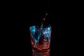 Pouring water into a rocks glass under blue and orange lights isolated on a black background Royalty Free Stock Photo