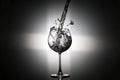 Pouring water in to the wine glass with rear light on black background Royalty Free Stock Photo