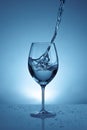 Pouring water into a transparent glass for wine. light blue background with water splashes Royalty Free Stock Photo