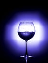 Pouring water into wine glass with black background blue white balance