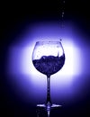 Pouring water into wine glass with black background blue white balance Royalty Free Stock Photo