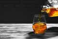 Pouring of whiskey from bottle into glass on wooden table Royalty Free Stock Photo