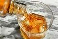 Pouring of whiskey from bottle into glass on wooden table, closeup Royalty Free Stock Photo