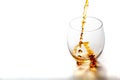 Pouring whiskey from bottle in to the glass without ice cubes on white table Royalty Free Stock Photo