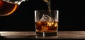 Pouring whiskey on a glass on vintage wooden table on a black background with copy pace area Royalty Free Stock Photo