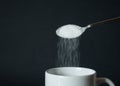 Pouring white sugar from spoon to white coffee cup, mug Royalty Free Stock Photo