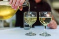 Pouring white wine into the glass against wooden table