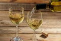 Pouring white wine in a glass on wooden background Royalty Free Stock Photo