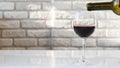 Pouring wine into a glass against a white brick wall,a man pours wine from a bottle.Natural red wine in a glass. Royalty Free Stock Photo