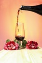 pouring wine in a glass with red roses with warm sunset background