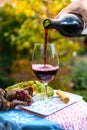 Pouring yound red beaujolais wine in glass during celebration of end of harvest and first sale release on third Thursday of Royalty Free Stock Photo