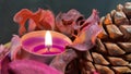 Pourple tealight and dry potpourri in a wooden bowl over a table with black background