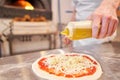 Pours olive oil. Baked tasty margherita pizza in Traditional wood oven in Naples restaurant, Italy. Original neapolitan Royalty Free Stock Photo